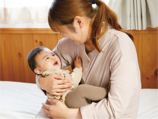 産後のお母さんが赤ちゃんを抱っこして笑い合っている様子