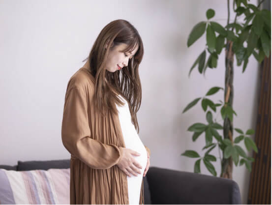 産前のお母さんが、胎児の居る自分のお腹に手を当てて愛しんでいる様子